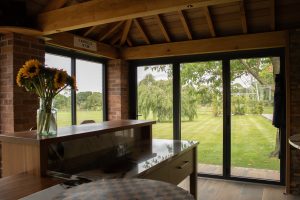 interior shot of country club with piano in foreground and 3 pane aluminium bifold doors in background