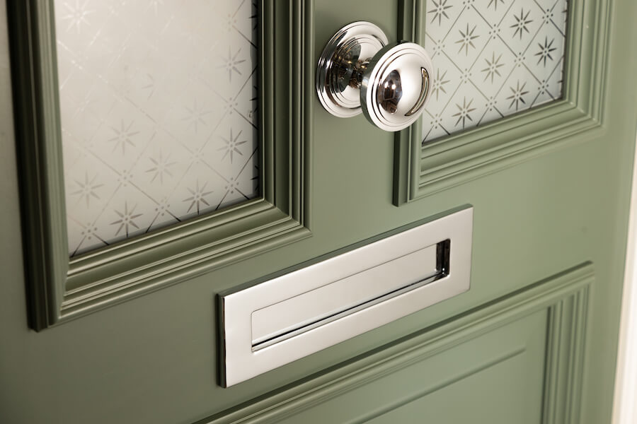 Close-up of a green Accoya timber door with a chrome letterplate and classic glazing details.